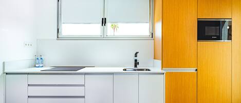 Una cocina moderna con un gran ventanal, muebles blancos y un horno empotrado.