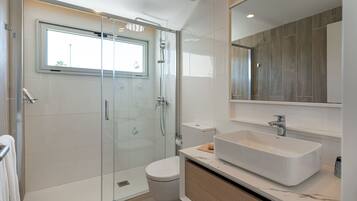 A modern bathroom with a glass-enclosed shower, a white sink, and a large mirror.