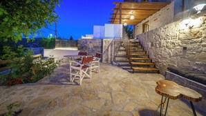 A stone patio with outdoor seating, a wooden staircase, and a stone wall. - Asion Suite Eros with Private Pool (Kato Asites)