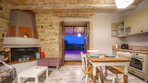 A rustic kitchen with a stone wall, wooden ceiling, and a view through an open doorway. - Asion Suite Eros with Private Pool (Kato Asites)