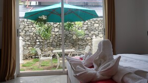 A hotel room with a view of a stone wall and a patio area with a table and chairs. - Meth Suites (Uswetakeiyawa)