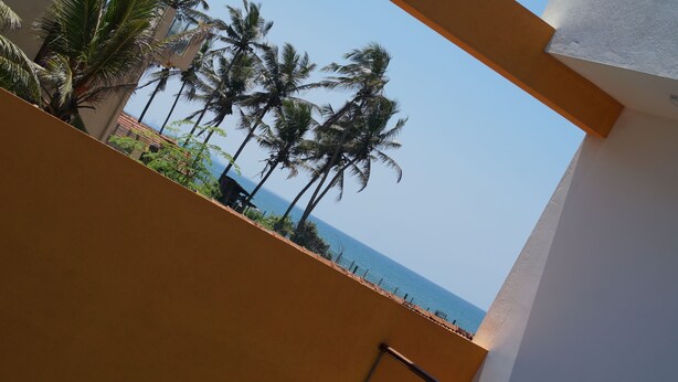 A balcony with a view of palm trees and the sea. - Meth Suites (Uswetakeiyawa)