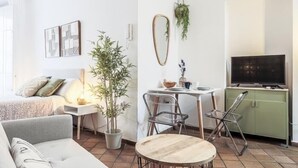 Een moderne woonkamer met een bank, een eettafel met stoelen, een televisie en een groen kastje.