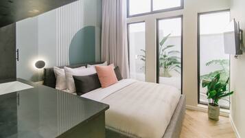 Ein modernes Schlafzimmer mit einem großen Bett, einem Nachttisch, einem Spiegel und einer Topfpflanze.