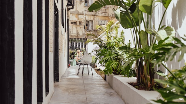 A narrow alleyway with a white wall on one side and a building on the other. There is a small table and chair set up in the middle of the alleyway. - Colorbox Ben Yehuda - Smart Hotel by Loginn Tel Aviv (Tel Aviv)