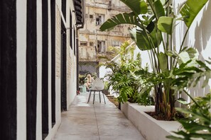 A narrow alleyway with a white wall on one side and a building on the other. There is a small table and chair set up in the middle of the alleyway. - Colorbox Ben Yehuda - Smart Hotel by Loginn Tel Aviv (Tel Aviv)
