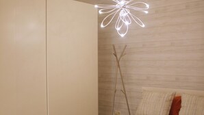 A bedroom with a bed, a wooden headboard, a bedside lamp, and a wall-mounted light fixture. - Central and cozy apartment in Seville - Wifi (Sevilla)