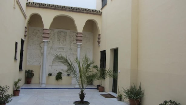 A courtyard with a tiled floor, potted plants, and a central fountain. - Central and cozy apartment in Seville - Wifi (Sevilla)