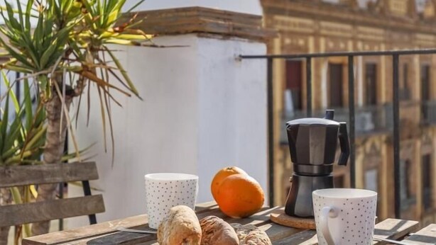 A balcony with a coffee maker, two mugs, a bowl of fruit, and a plant. - Pure Sevilla - Arenal - 2 bed common terrace 5 px (Sevilla)