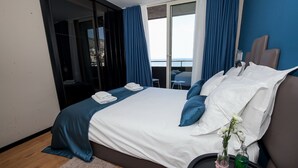 Une chambre d’hôtel moderne avec un grand lit, une vue sur la mer et un balcon.