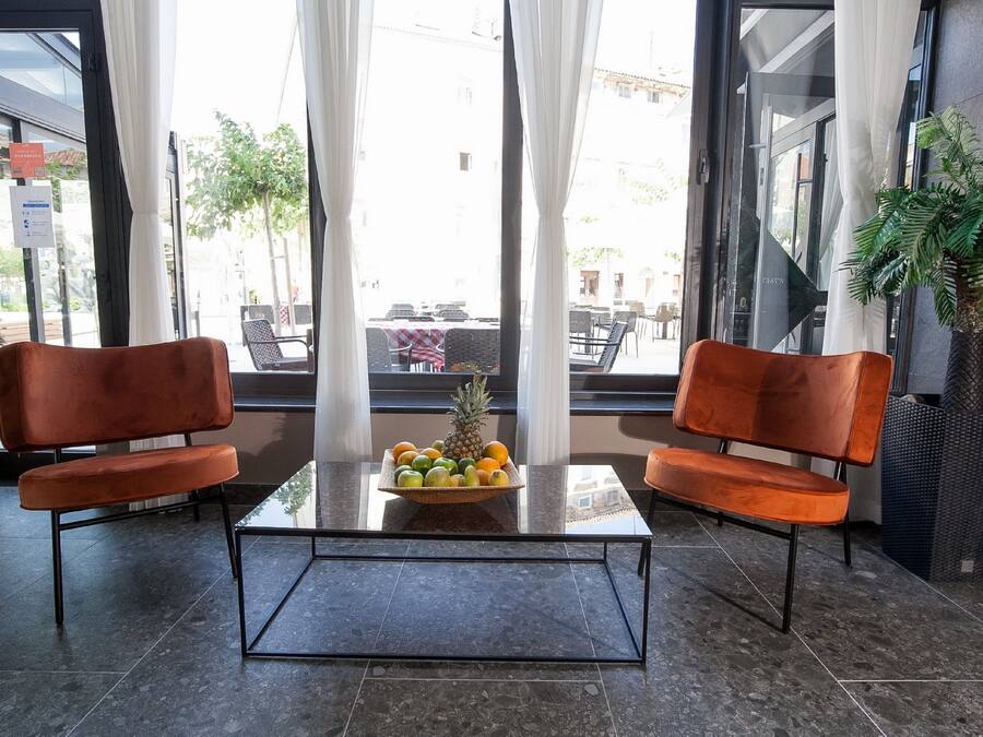 Ein Sitzbereich mit zwei orangefarbenen Sesseln, einem Glastisch und einer Obstschale.