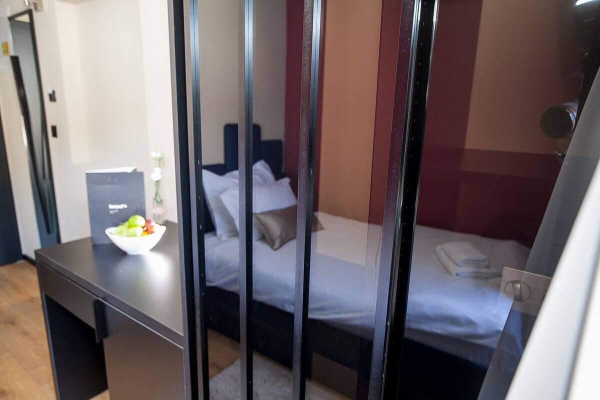 Une chambre d’hôtel avec un lit, un bureau avec un ordinateur portable et un saladier de fruits.