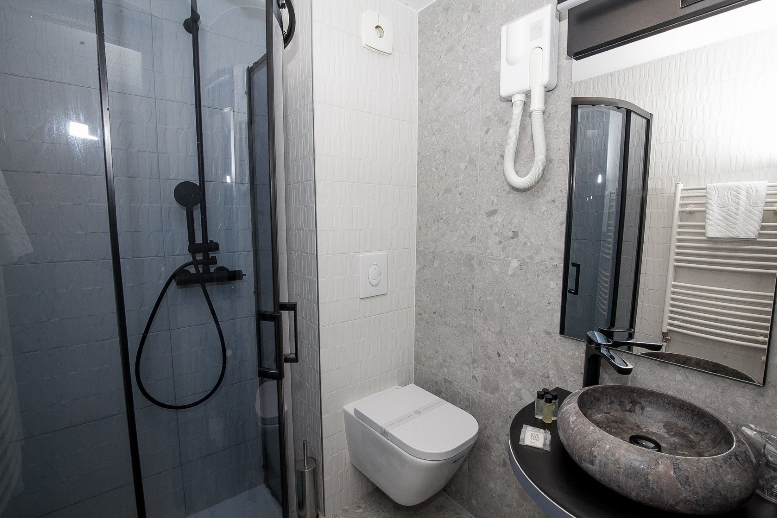 A modern bathroom with a glass-enclosed shower, a white toilet, and a sink with a large, round basin.