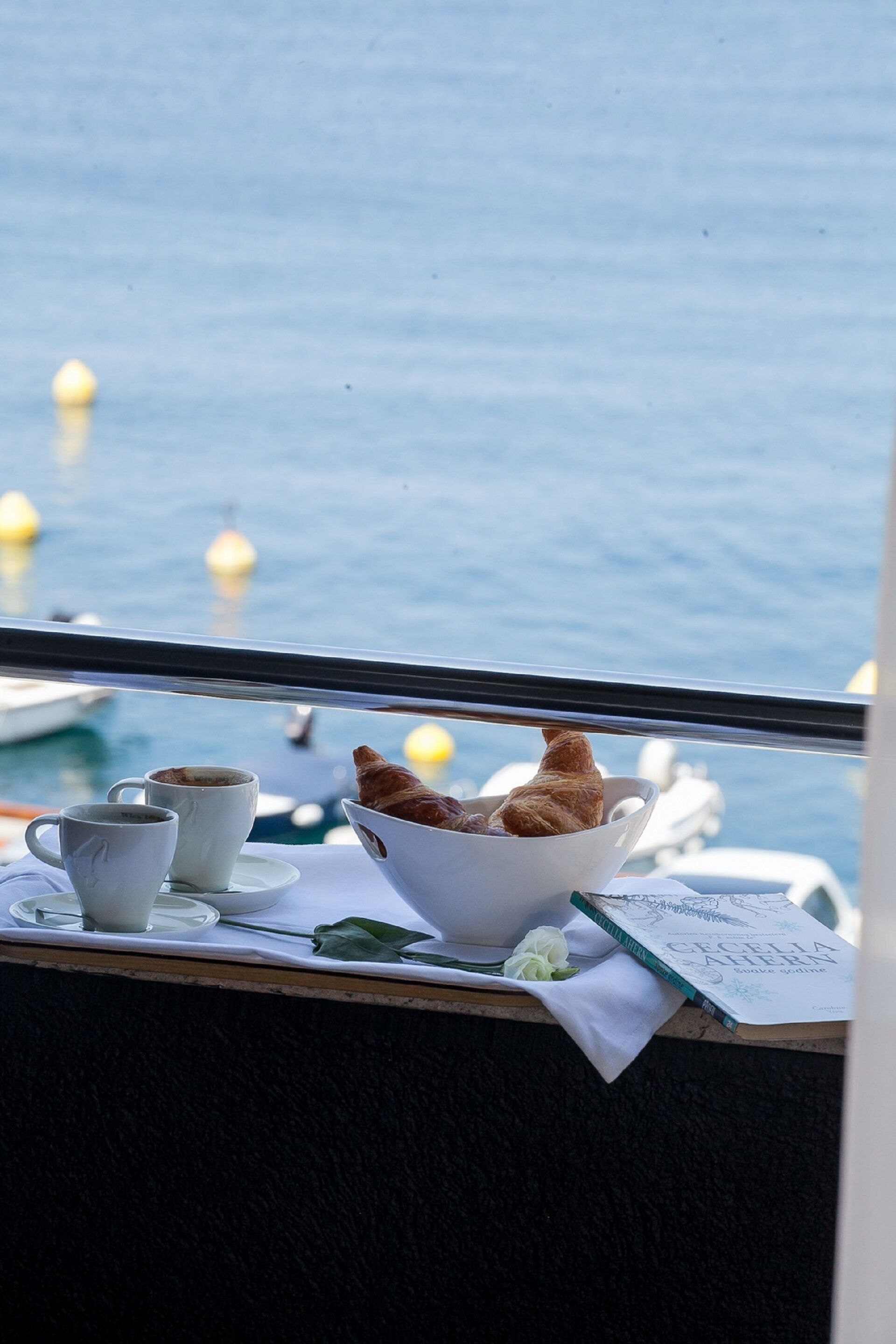 A table with a croissant, two cups, and a book titled "Cecilia Bern".