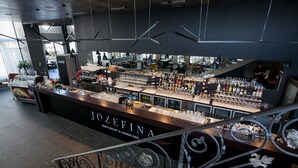 Un espace bar avec un comptoir où sont exposées différentes bouteilles et différents verres, et une enseigne indiquant : « RESTAURANT ET BAR LOUNGE JOZEFINA ».