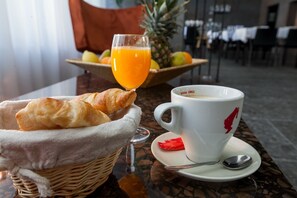 Een ontbijtje met croissants, sinaasappelsap en een beker met lepel op een tafel.