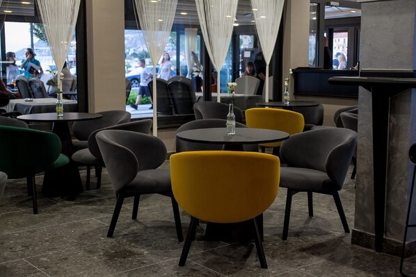 A modern restaurant interior with round tables and chairs, some with yellow cushions. - Bura 45 Boutique Hotel (Senj)