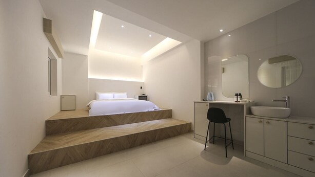 Un baño moderno con un espejo grande, un lavamanos y una silla.
