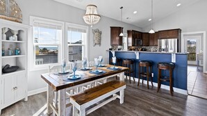 Cucina con tavolo in legno, sgabelli da bar e isola blu.