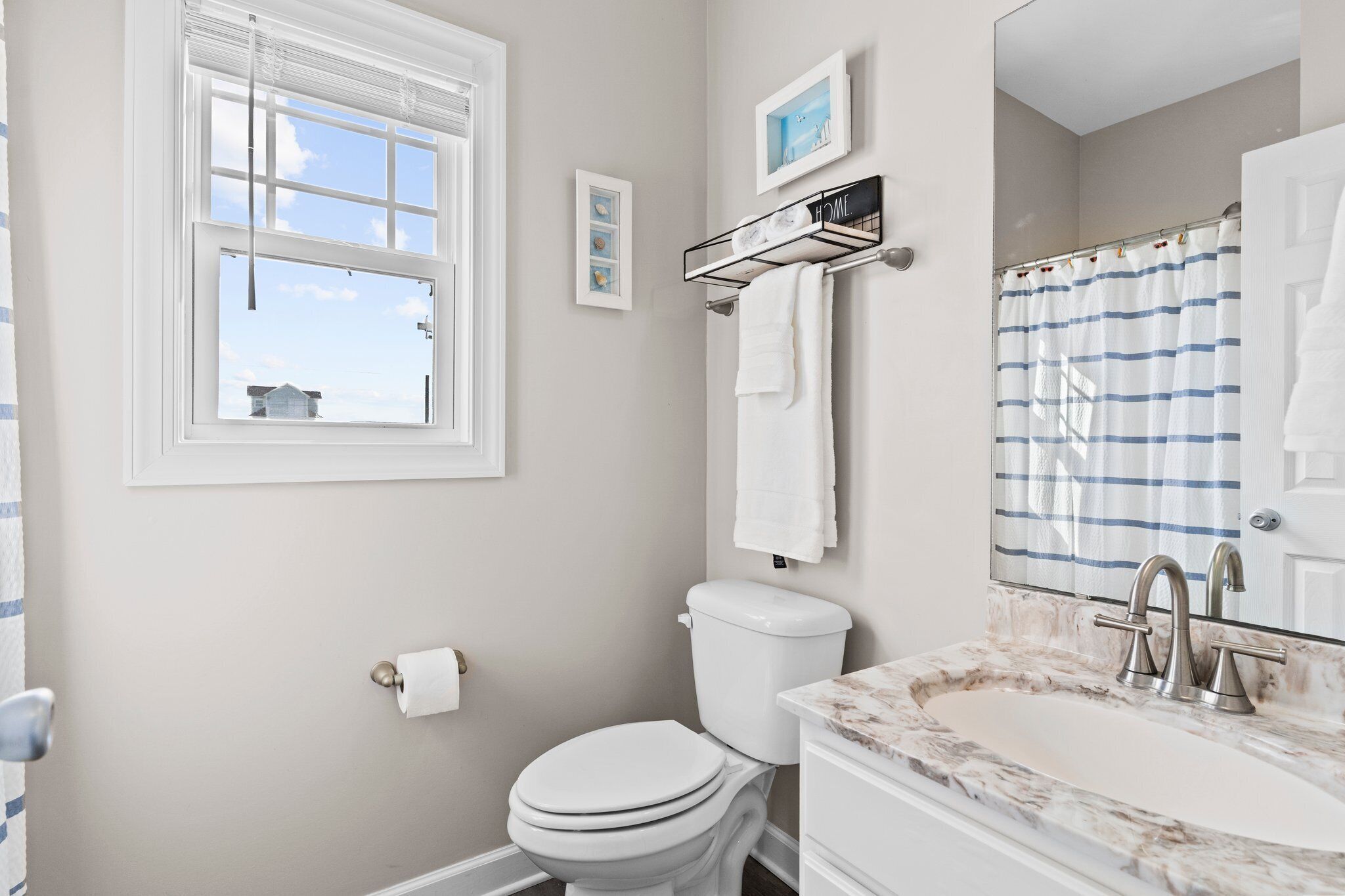A bathroom with a toilet, sink, and window.