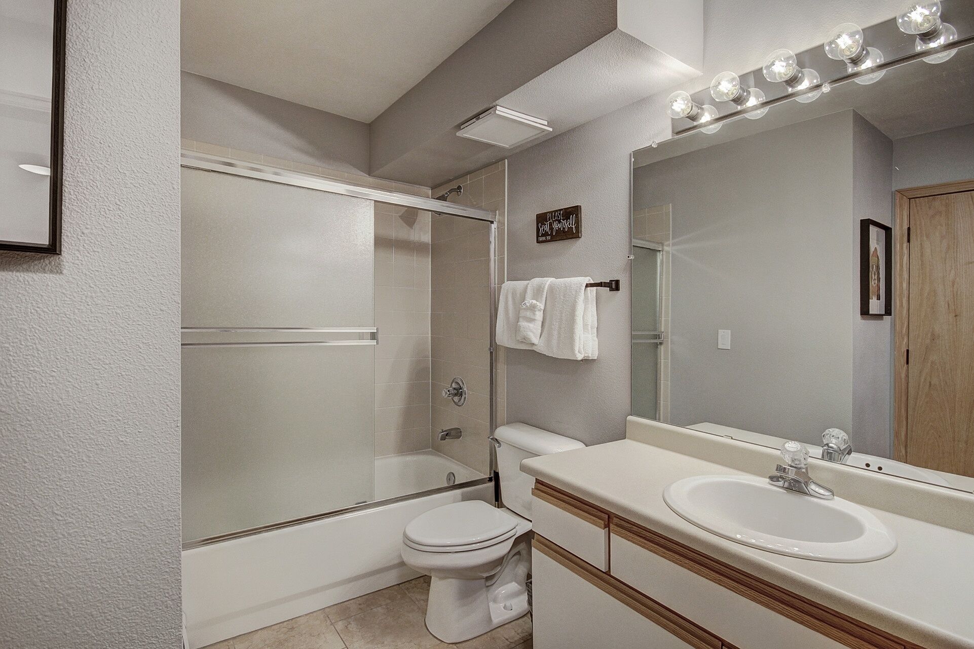 Une salle de bain moderne avec une douche à parois de verre, des toilettes, un lavabo avec un miroir et une serviette accrochée au mur.