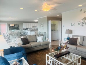 A spacious living room with a sofa, a coffee table, and a dining area with chairs. - Elegant Egret 4 Bedroom Home by RedAwning (Supply)