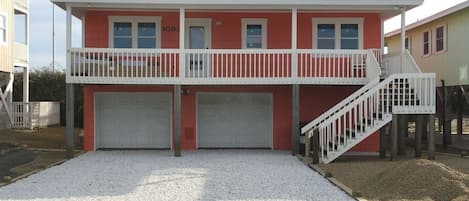 Et toetagers hus med en balkon, to garageporte og en trappe, der fører op til øvre etage.