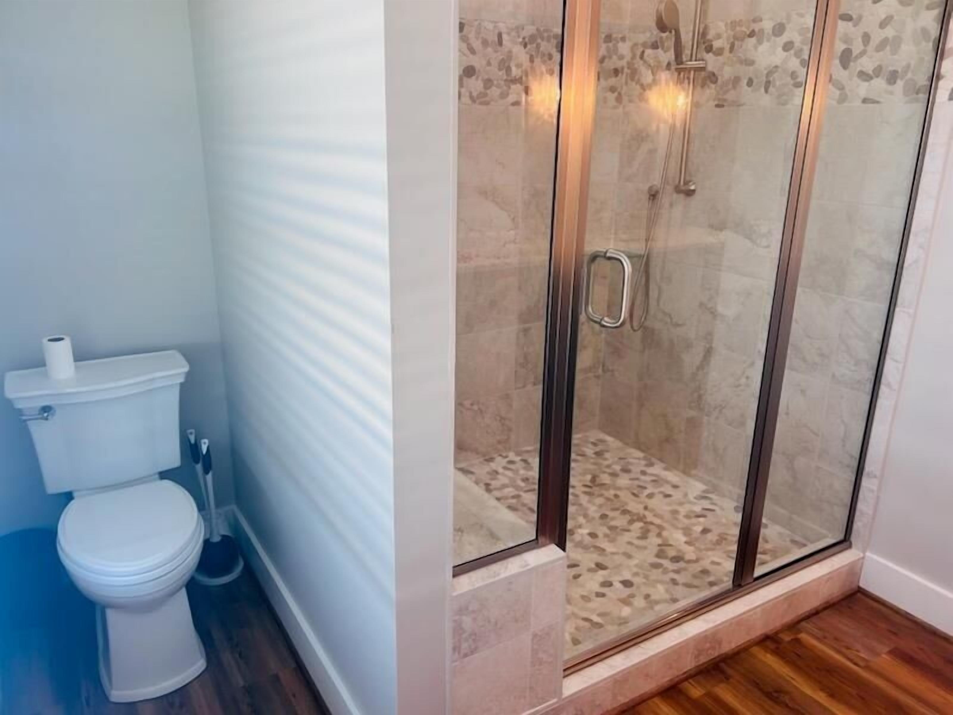 A bathroom with a toilet, a shower with glass doors, and a tiled floor.