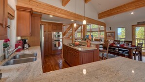 A spacious kitchen with wooden beams, granite countertops, and a central island. - Northstar Conifer Luxury 5 Bedroom Home by RedAwning (Truckee)