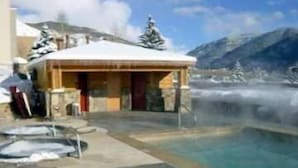 A hot spring area with a wooden building, a pool, and snow-covered mountains in the background. - Sunvail S 24d 3 Bedroom Condo by RedAwning (Vail)