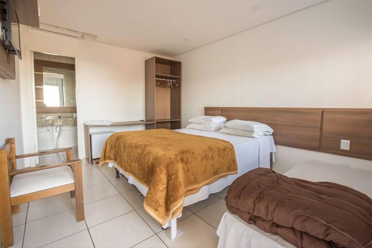 A bedroom with a bed, a chair, a wardrobe, and a small table.