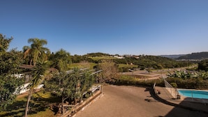 Vista de una zona residencial con camino pavimentado, piscina y abundante vegetación.