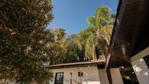 Un edificio blanco con techo plano, rodeado de varios árboles y una escalera que conduce a un nivel superior.