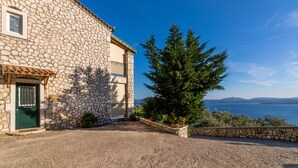 Un bâtiment en pierre avec une porte verte, une fenêtre et une vue sur la mer.