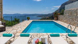A pool with clear blue water, surrounded by stone tiles and a stone wall. There are lounge chairs with towels and a potted plant. - Villa Marianthi with private pool  (2 Bedrooms, Sleeps 4) (Corfu, Peloponnisos Dytiki Ellada ke Ionio)