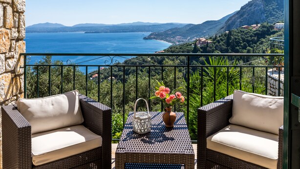 A balcony with wicker furniture, a vase with flowers, and a view of the sea and mountains. - Villa Marianthi with private pool  (2 Bedrooms, Sleeps 4) (Corfu, Peloponnisos Dytiki Ellada ke Ionio)
