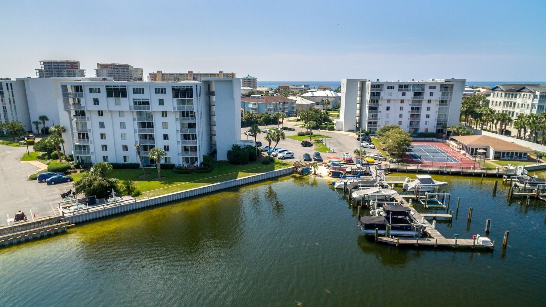 Un puerto deportivo con barcos amarrados, rodeado de edificios de varios pisos con balcones y una vista despejada del agua.