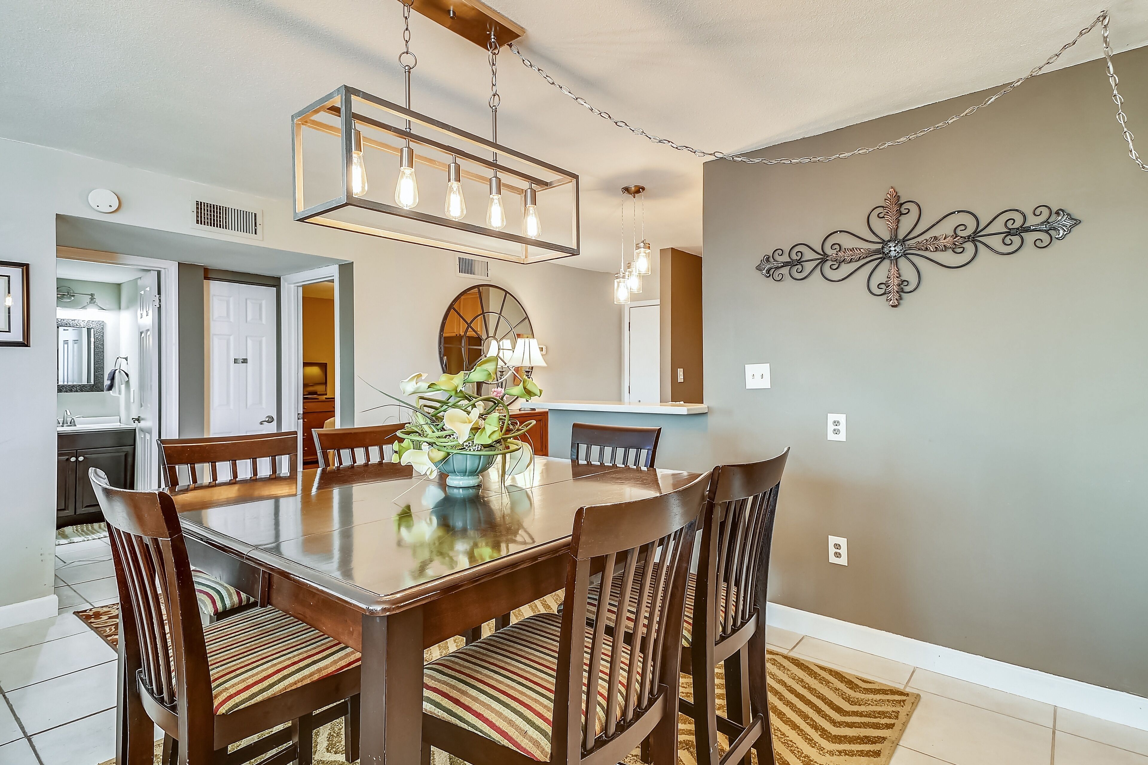 A dining area with a wooden table, chairs, and a hanging light fixture.
