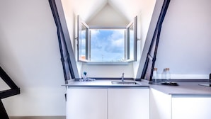 A modern kitchen with a skylight, white cabinets, and a stainless steel sink.