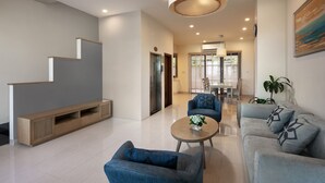 A modern living room with a staircase, a dining area, and a sofa set. - La Batisse Resort Halong (Bai Chay)