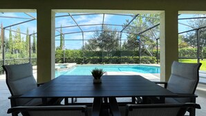A covered outdoor area with a pool, a table, and chairs. - Private Pool Oasis!  Ultimate Family Vacation! Solterra Resort Near Disney! (Davenport)