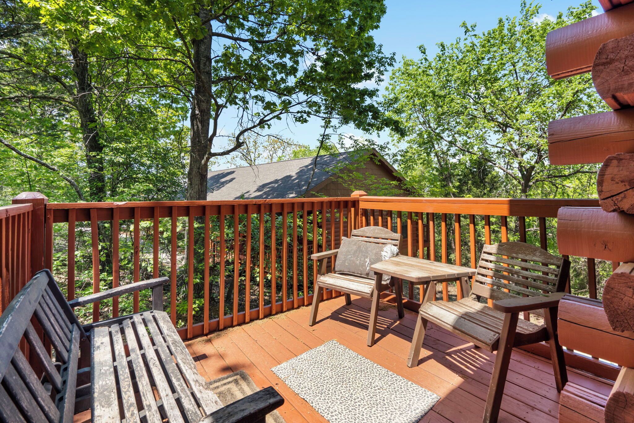 Une terrasse en bois avec un banc en bois, une table et deux chaises.