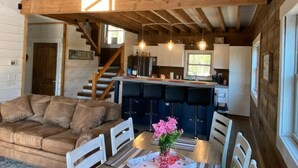 A rustic cabin interior with a dining area, kitchen, and a loft bedroom. - Rocky Top Retreat-Decorated for Christmas Near NPS (Victor)