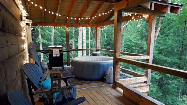 A wooden deck with outdoor seating and a hot tub, surrounded by trees. - Rocky Top Retreat-Decorated for Christmas Near NPS (Victor)