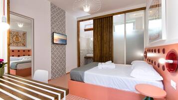 A modern hotel room with a bed, bedside table, and a large mirror.