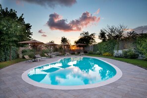 A swimming pool with lounge chairs and umbrellas, surrounded by a landscaped garden. - Maison Di Fiore Park  (Ercolano)
