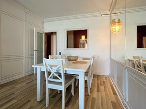 Enjoy meals in this dining area with a table and chairs, surrounded by a mirror and chandelier.