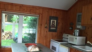 Eine Küche mit Holzvertäfelung, einem Fenster mit Blick auf einen Garten, einer Mikrowelle, einem Spülbecken und einem Deckenventilator.