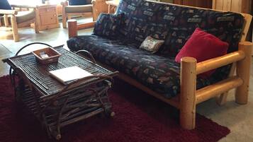 A cozy cabin interior with a wooden sofa, a small table, and a red rug.