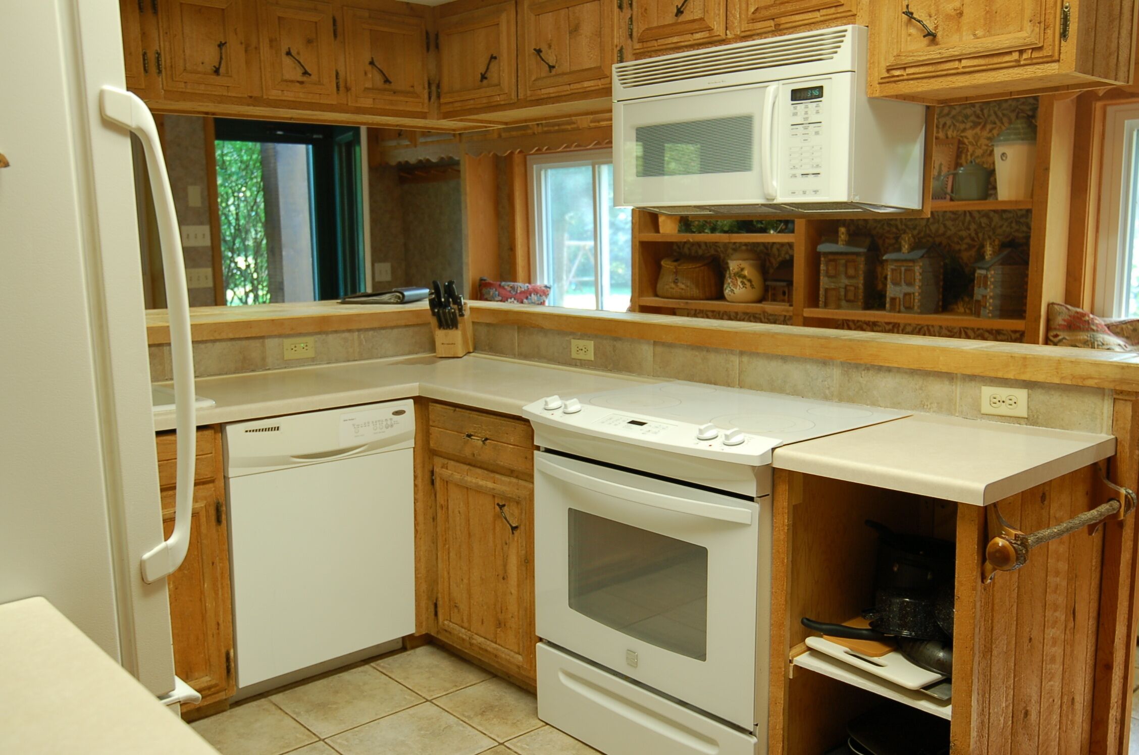 A kitchen with wooden cabinets, a microwave, a stove, and a dishwasher.